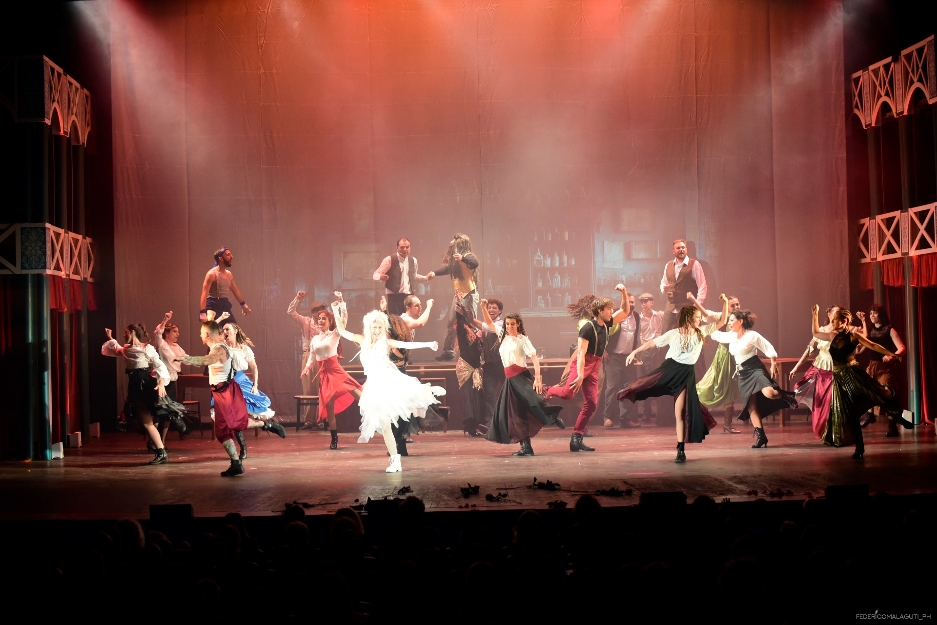 Grande coreografia di gruppo con ballerini in gonne colorate sotto luci calde