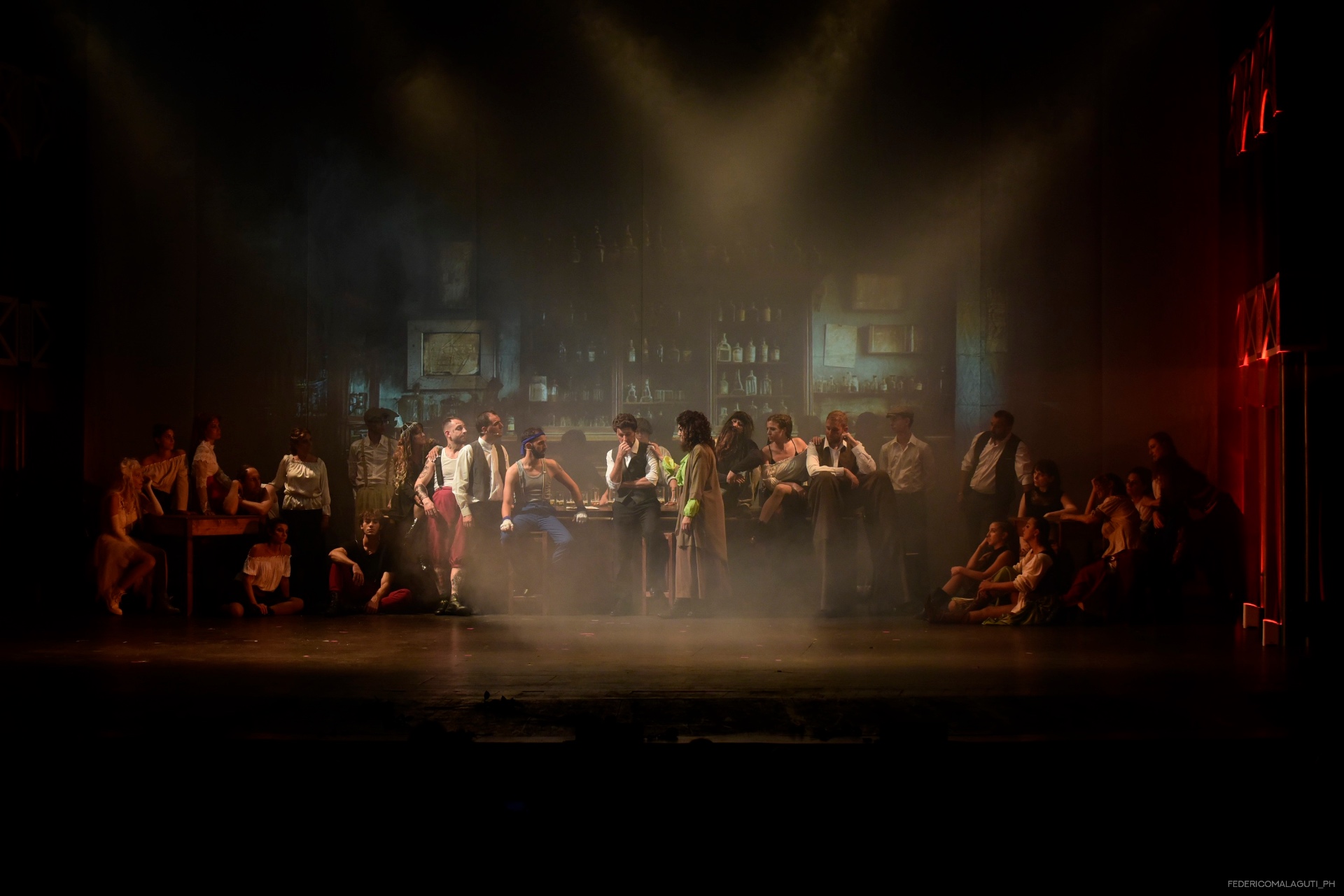 L'intera compagnia in tableau vivant intorno al bancone del bar avvolto nel fumo