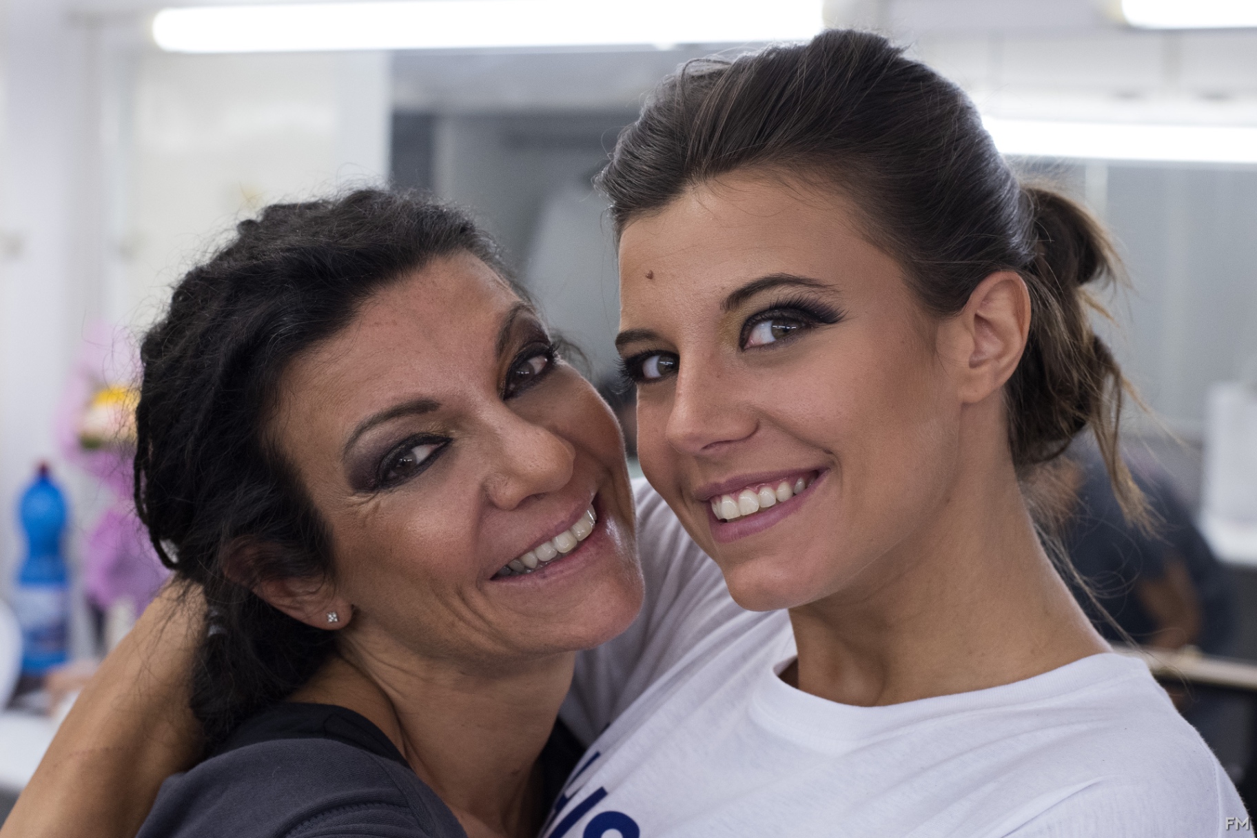 Due donne sorridenti guancia a guancia con trucco di scena marcato
