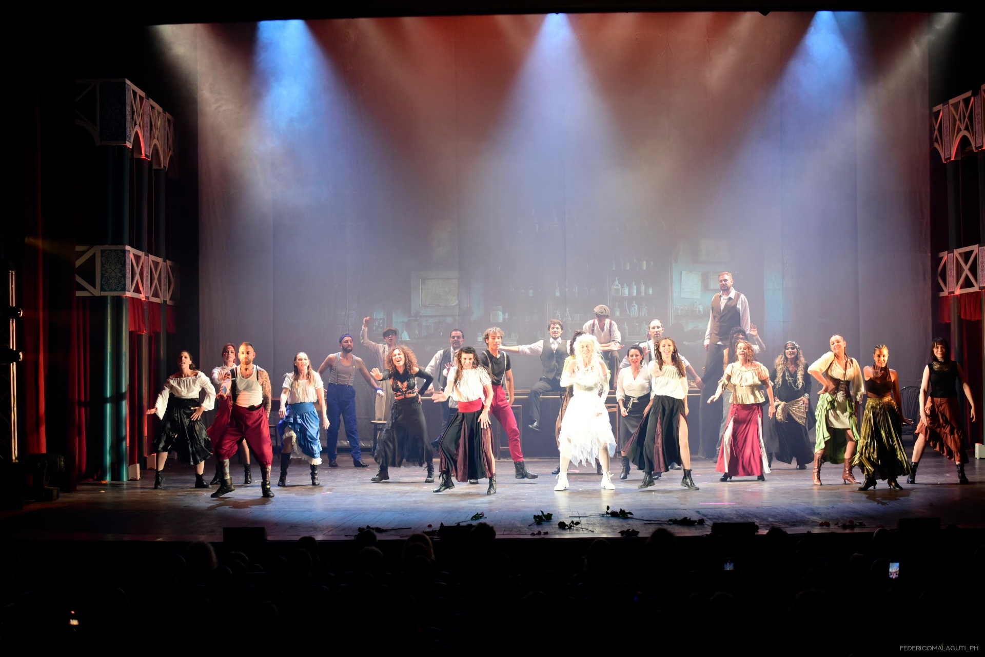 Cast al completo in formazione ampia sul palcoscenico con fumo e luci teatrali