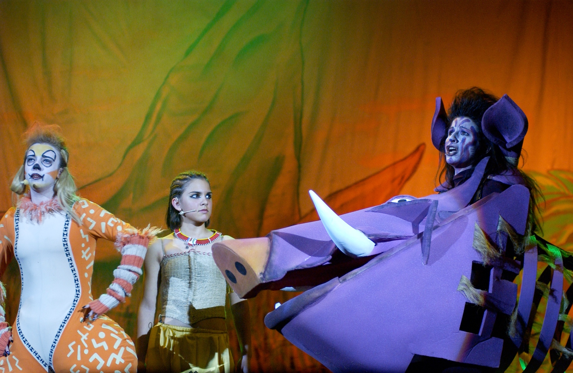 Timon, Pumbaa e Simba in scena con costumi arancioni e viola