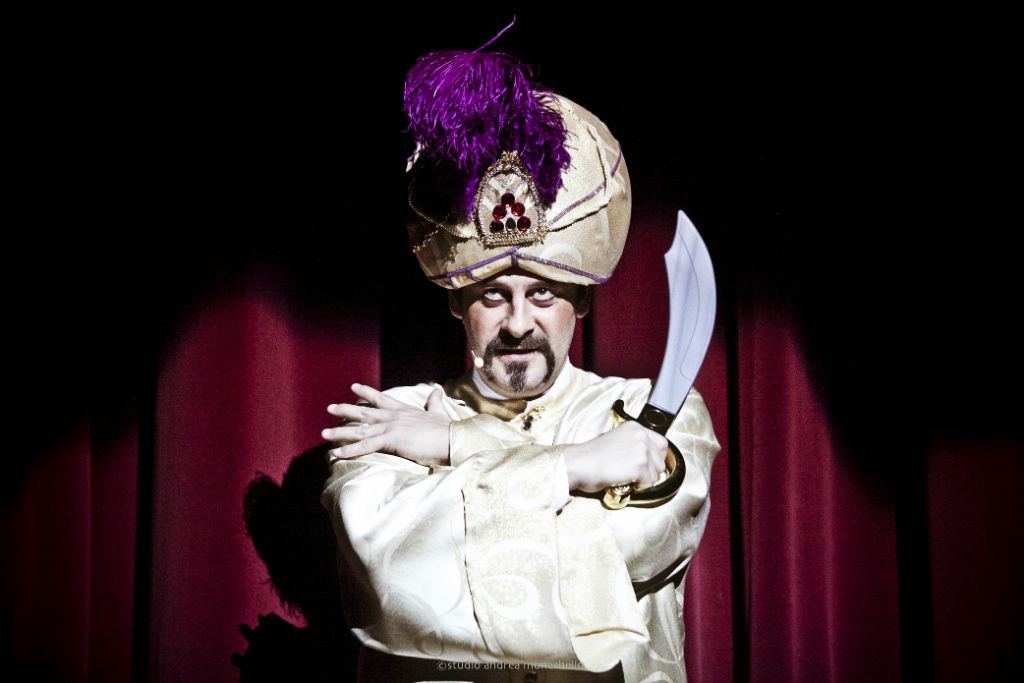 Uomo con turbante crema e piume viola impugna una scimitarra