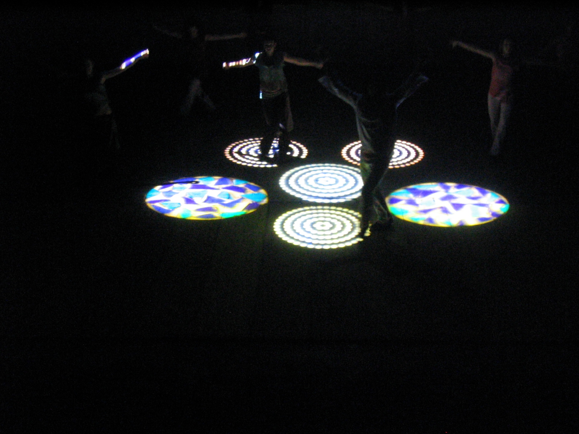 Danzatori nel buio con cerchi luminosi proiettati sul palco