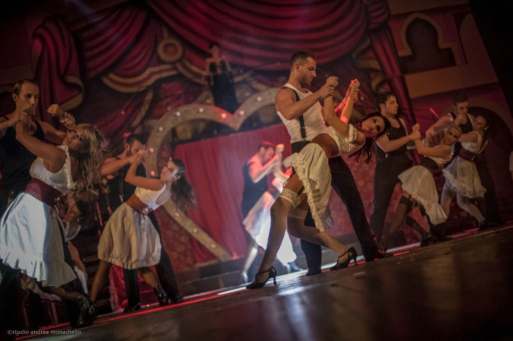 Coppie di ballerini in coreografia di gruppo con luci rosse