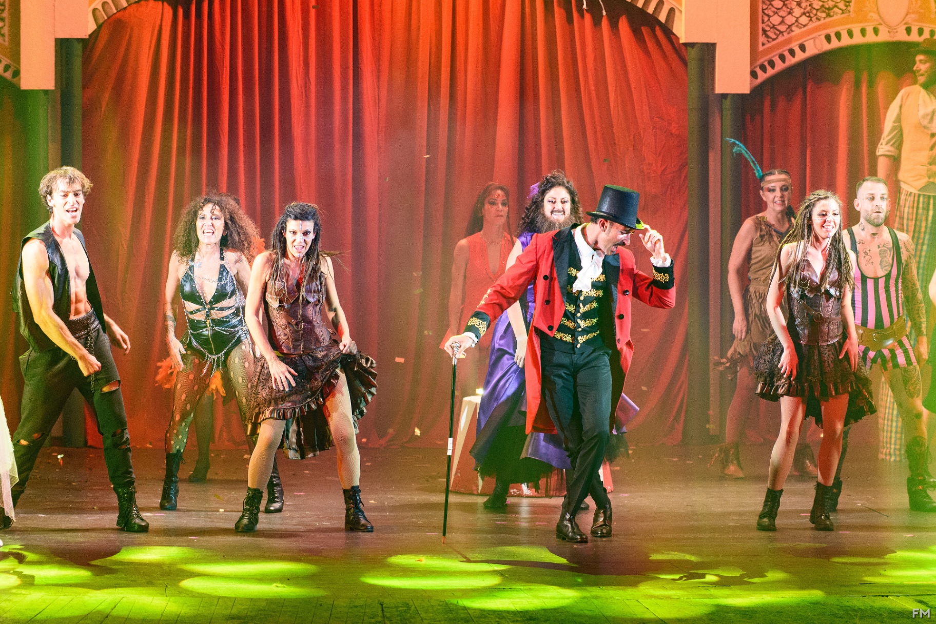 Primo piano del direttore del circo tra il cast di freaks in costumi elaborati