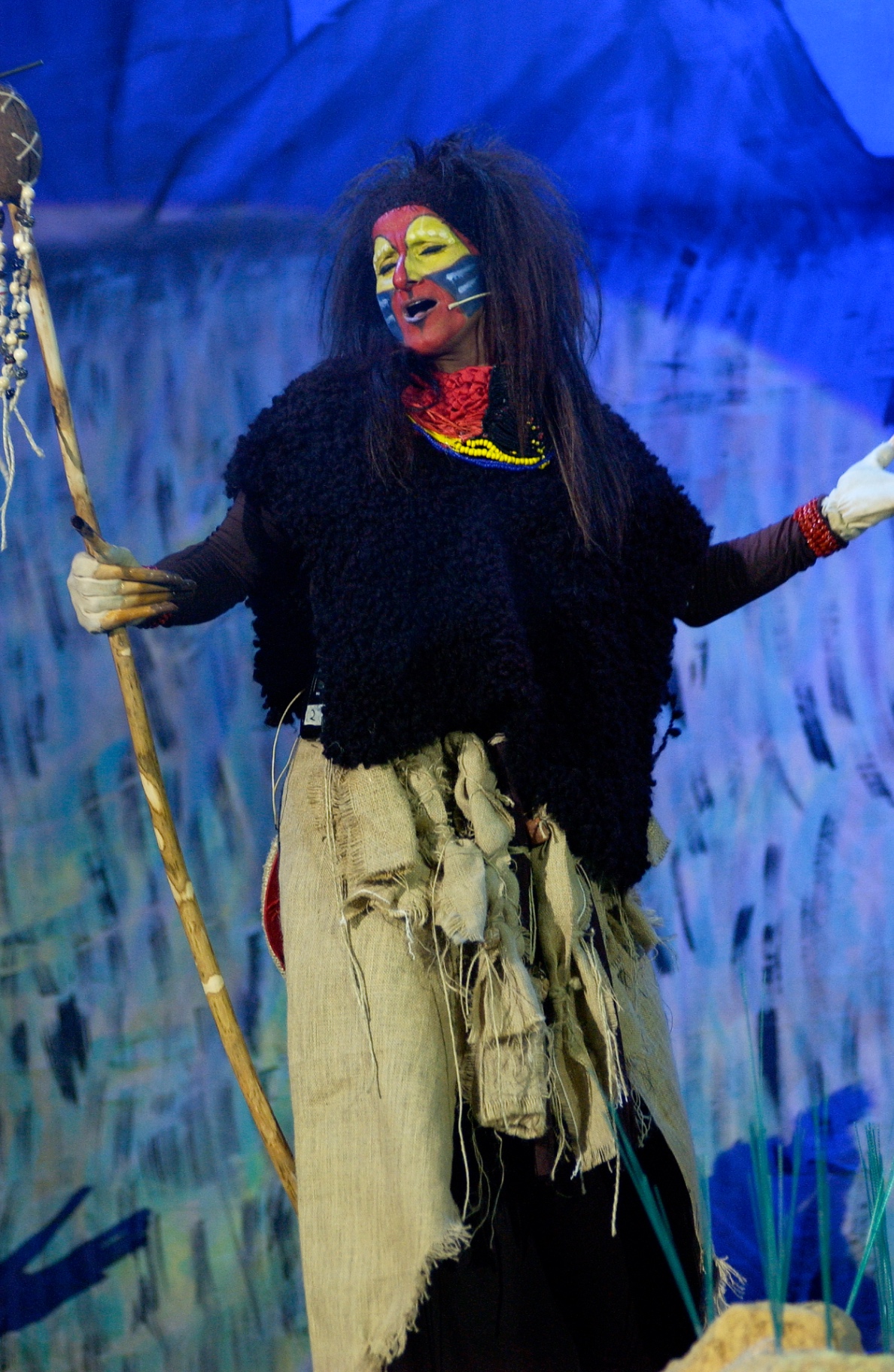 Rafiki in piedi con bastone rituale canta nella savana blu