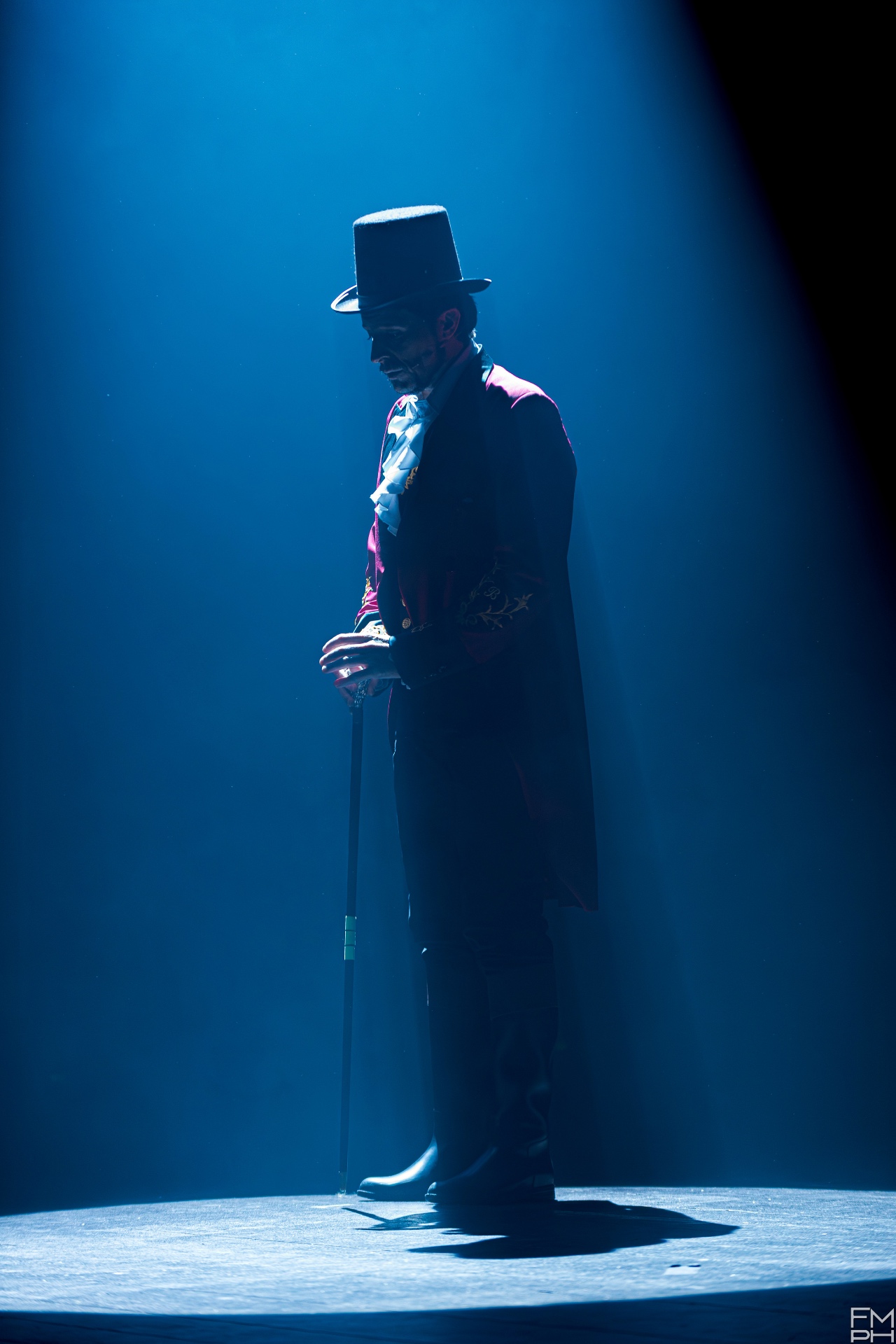 Showman in controluce blu con cilindro e bastone da passeggio, silhouette isolata