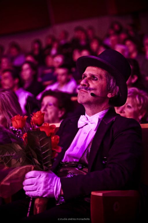 Spettatore in cilindro fra il pubblico con mazzo di rose rosse
