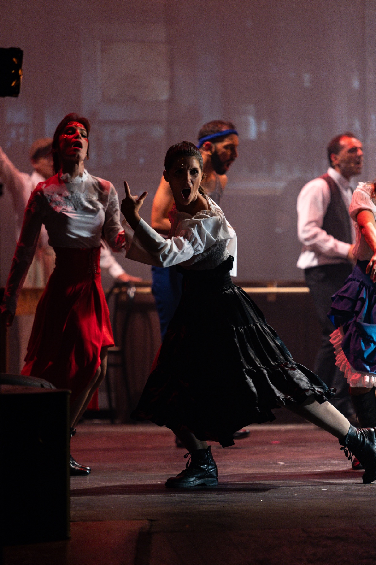 Ballerina in nero e bianco in posa teatrale al centro di una scena corale