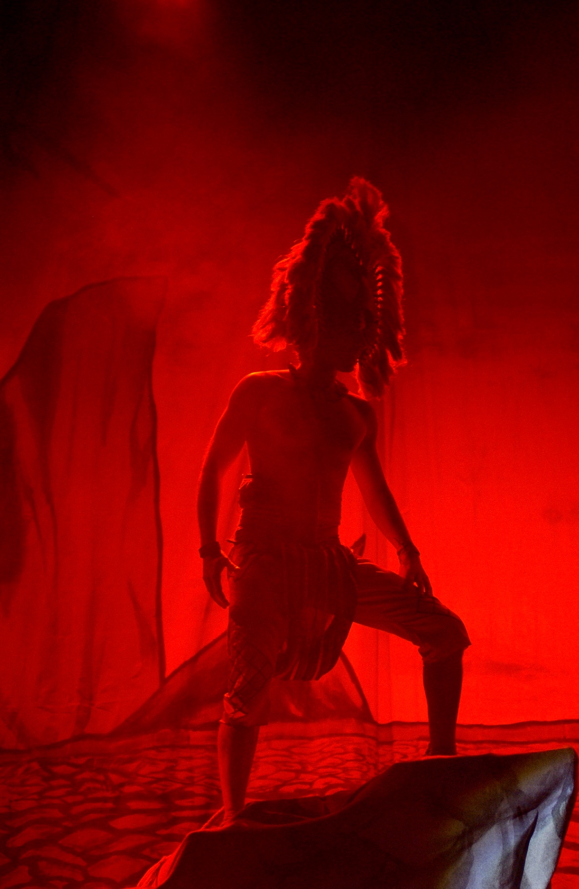 Silhouette di danzatore con copricapo di piume nella luce rossa