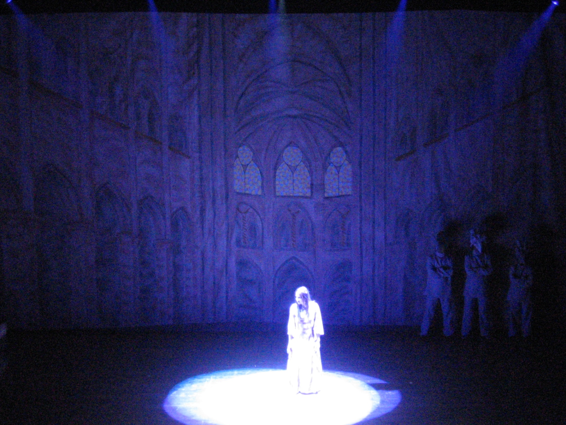 Donna in abito bianco in un cerchio di luce davanti alla cattedrale blu notte