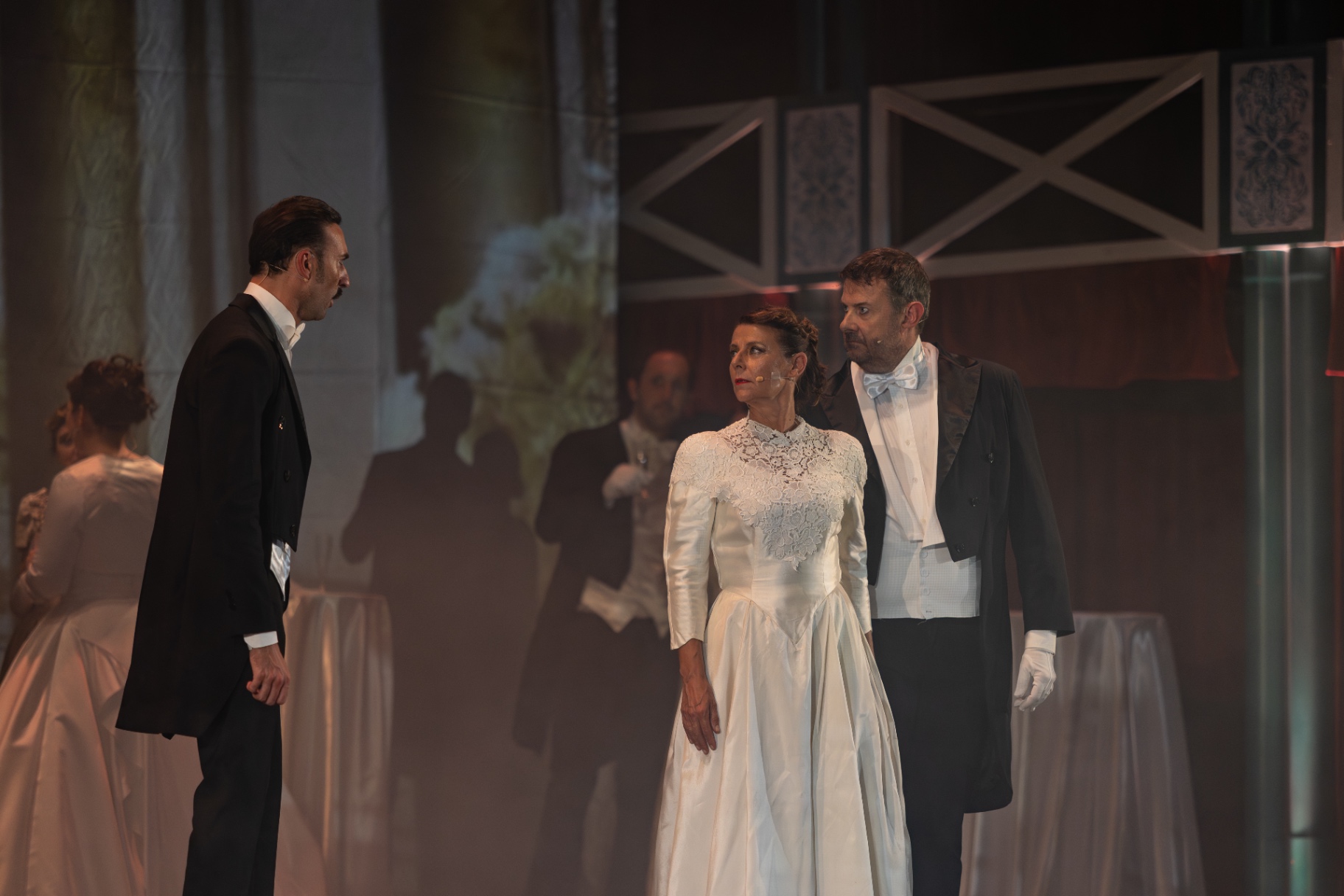 Padre della sposa in frac osserva la coppia elegante in abiti da cerimonia bianchi