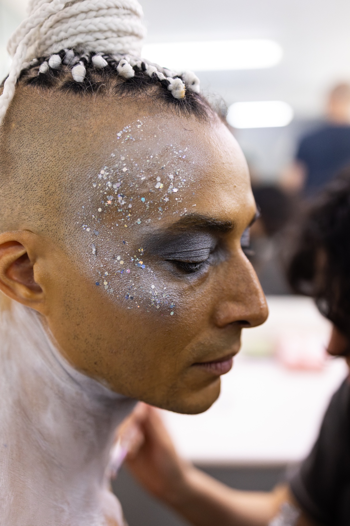 Profilo di ballerino con trecce bianche raccolte in alto e glitter argentato applicato sulla tempia