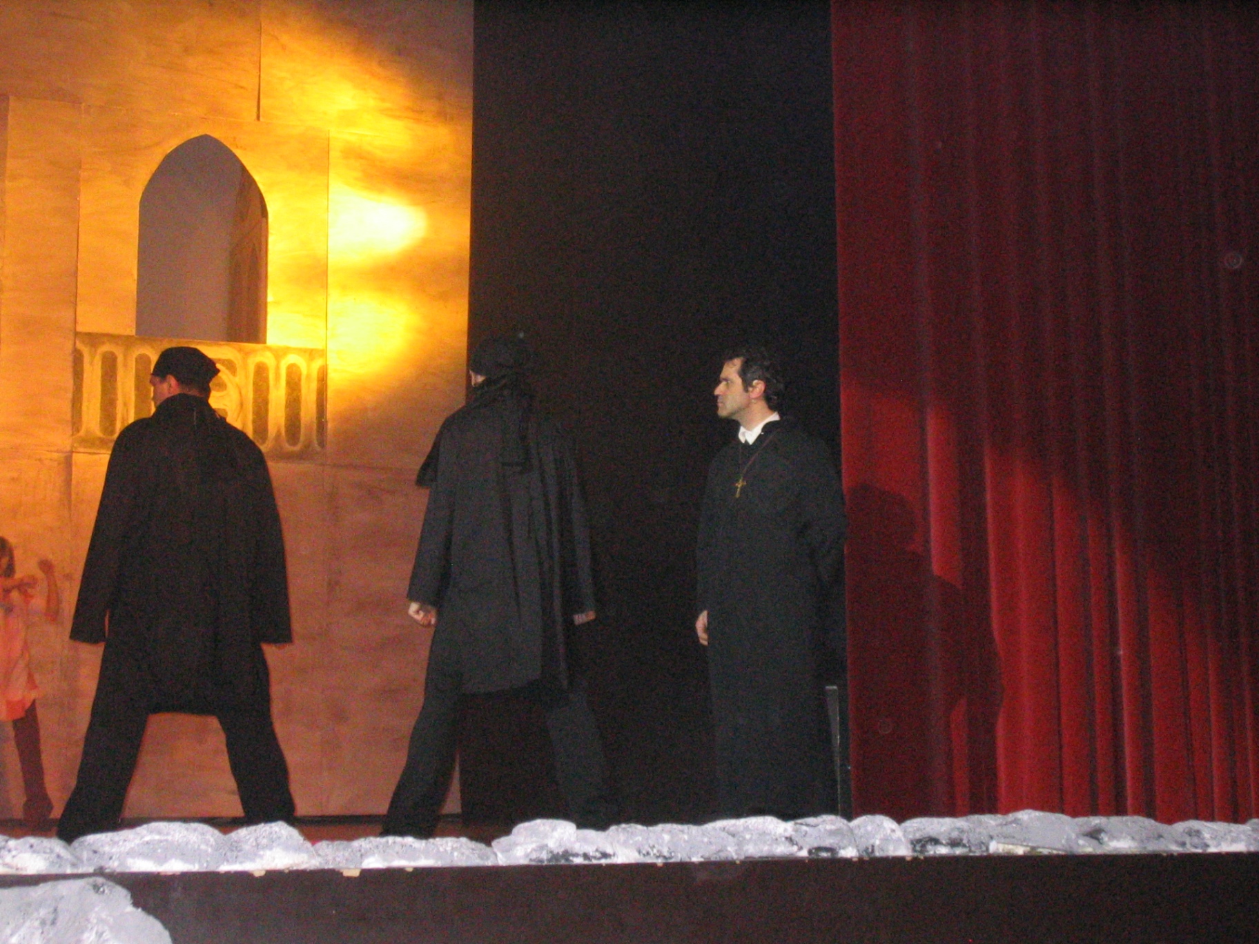 Tre religiosi in nero vicino al sipario rosso del palco